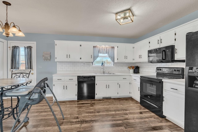 kitchen with a chandelier, white cabinetry, hanging light fixtures, and black appliances