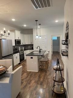 kitchen featuring sink, stainless steel appliances, pendant lighting, a kitchen island with sink, and white cabinets