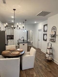 dining space with dark wood-type flooring and an inviting chandelier