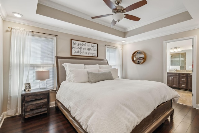 bedroom with ensuite bathroom, a tray ceiling, ceiling fan, crown molding, and dark wood-type flooring