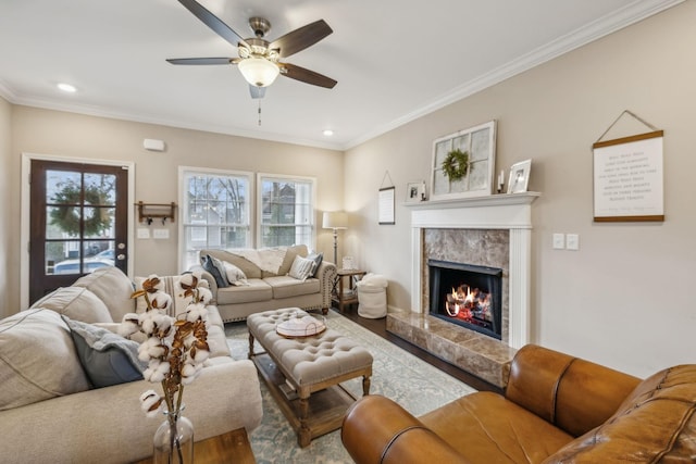 living room featuring a fireplace, wood-type flooring, ceiling fan, and crown molding