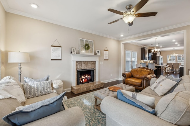 living room featuring wood-type flooring, ceiling fan with notable chandelier, crown molding, and a premium fireplace