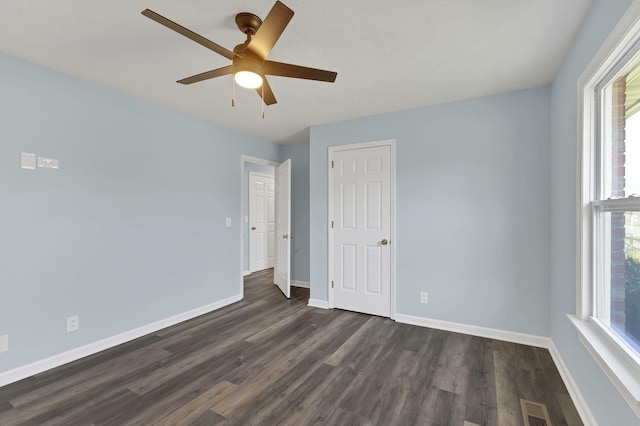 empty room with ceiling fan and dark hardwood / wood-style flooring