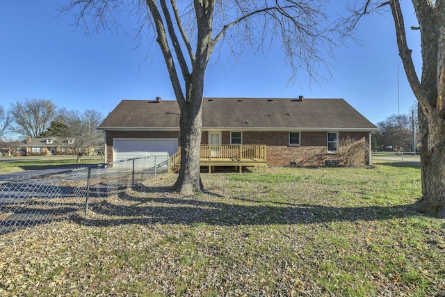 rear view of property featuring a lawn, a garage, and a wooden deck