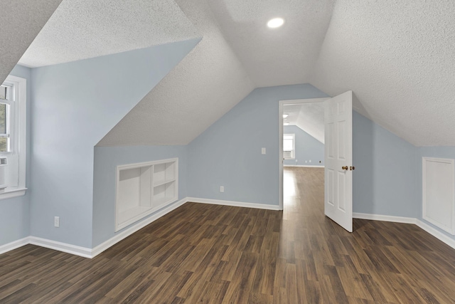 additional living space with a textured ceiling, built in features, vaulted ceiling, and dark hardwood / wood-style floors