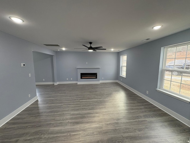 unfurnished living room featuring dark wood-type flooring and ceiling fan