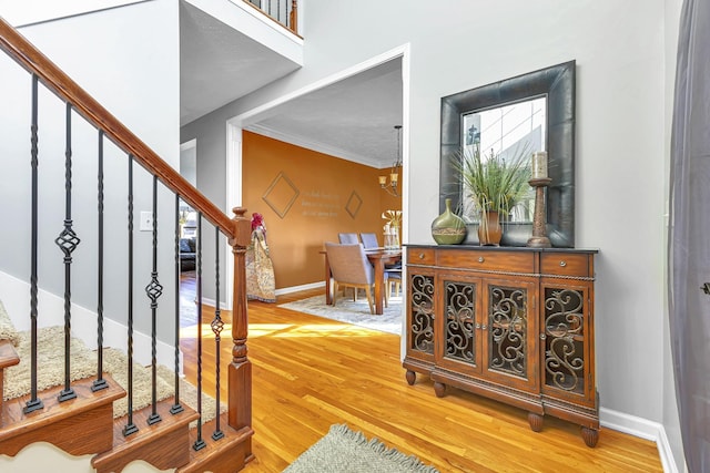 foyer entrance featuring wood-type flooring, ornamental molding, and an inviting chandelier