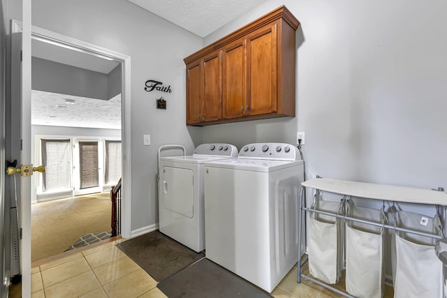 clothes washing area featuring cabinets, light tile patterned floors, washing machine and dryer, and a textured ceiling