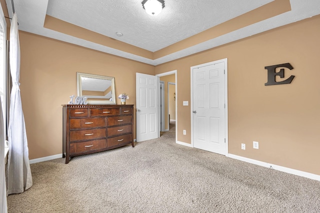 bedroom with light carpet, a textured ceiling, and a tray ceiling