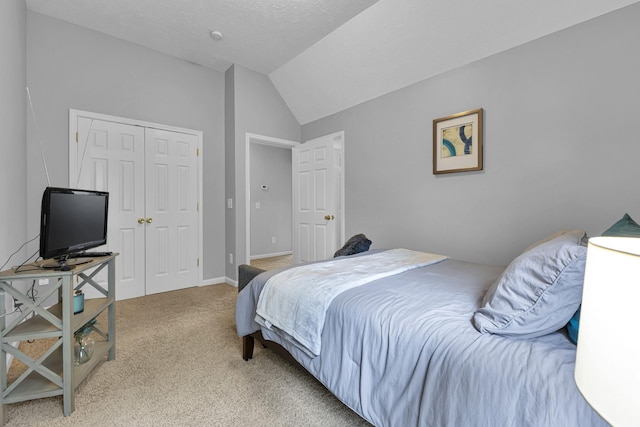 carpeted bedroom featuring lofted ceiling, a textured ceiling, and a closet