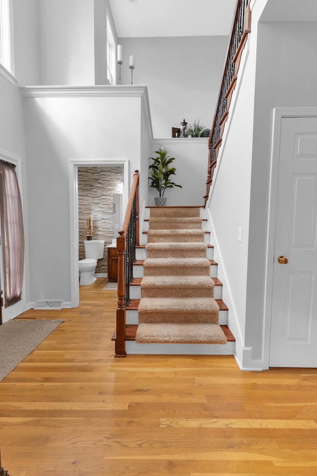 staircase featuring wood-type flooring and a high ceiling