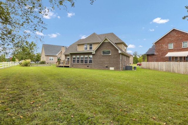 back of house featuring a wooden deck, a yard, and central AC