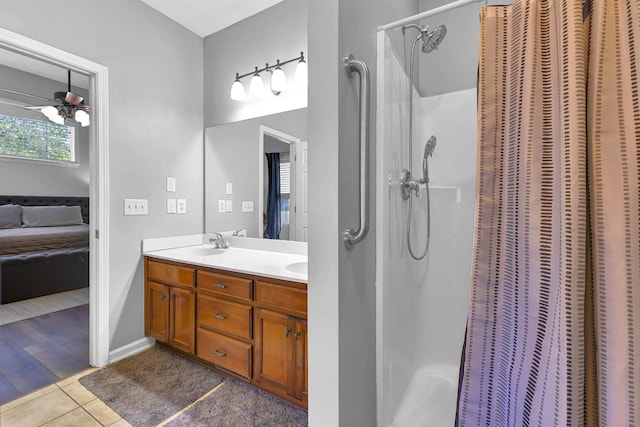 bathroom with tile patterned flooring, ceiling fan, walk in shower, and vanity