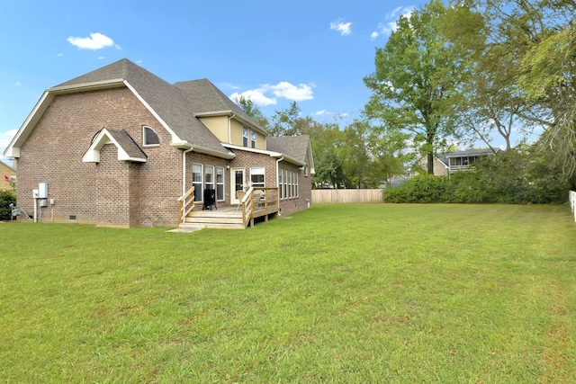 rear view of house featuring a lawn and a wooden deck