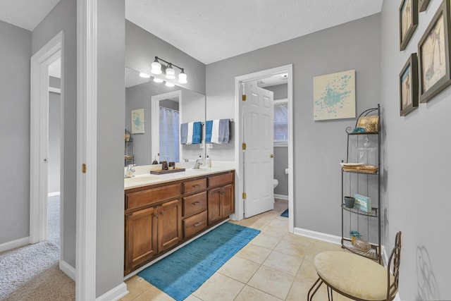 bathroom featuring tile patterned flooring, a textured ceiling, vanity, and toilet