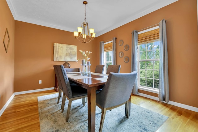 dining area with crown molding, an inviting chandelier, and light wood-type flooring