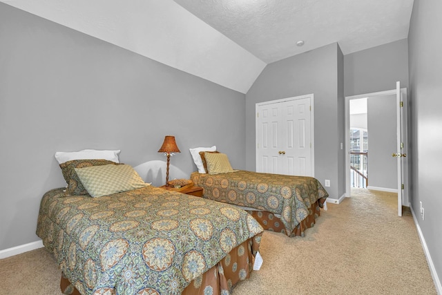 bedroom with a textured ceiling, light carpet, a closet, and lofted ceiling