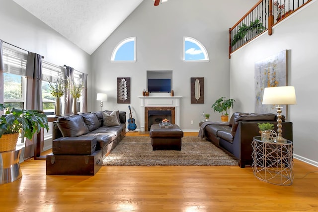 living room with light wood-type flooring, a textured ceiling, and high vaulted ceiling