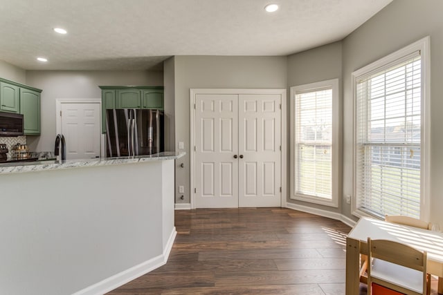 kitchen featuring stainless steel appliances, dark wood-type flooring, green cabinets, and light stone counters