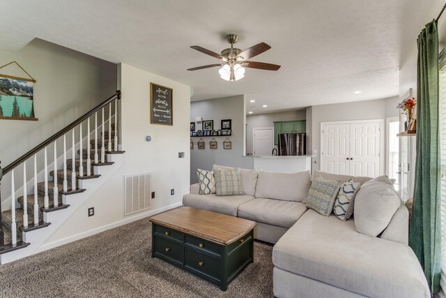 living room featuring dark carpet, a textured ceiling, and ceiling fan