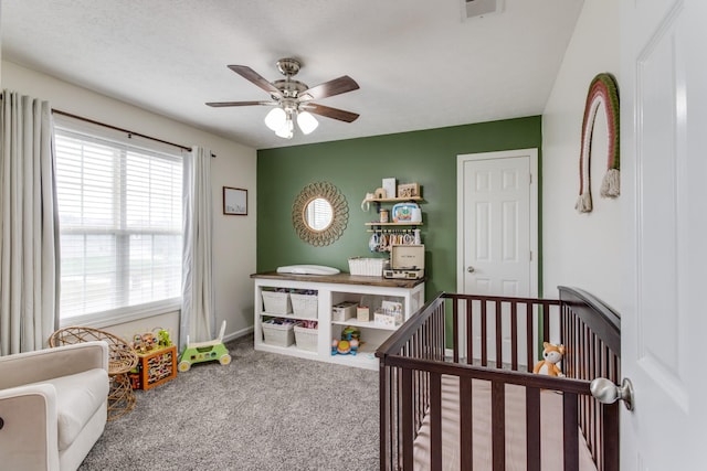 carpeted bedroom with a nursery area and ceiling fan