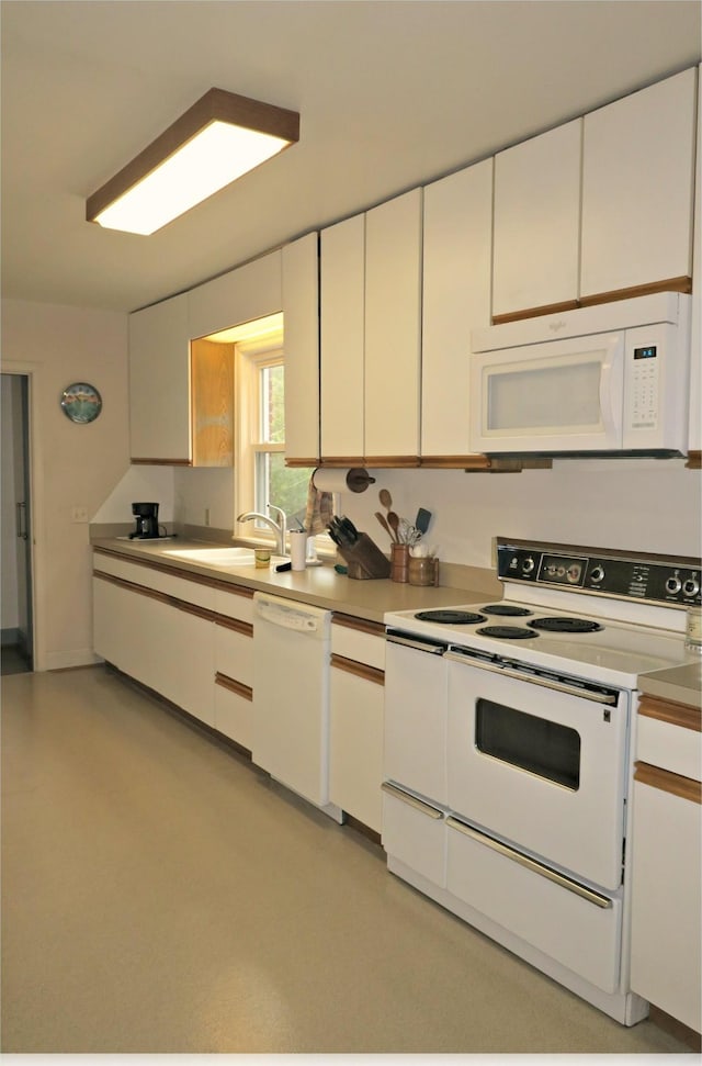 kitchen with white appliances, white cabinetry, and sink