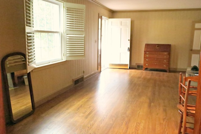 interior space featuring a healthy amount of sunlight, crown molding, radiator heating unit, and light hardwood / wood-style floors