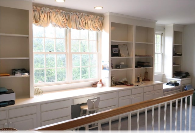 kitchen with a healthy amount of sunlight, white cabinets, and built in desk