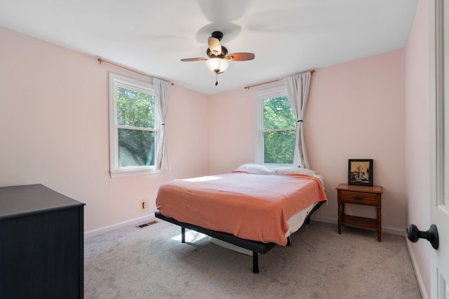 carpeted bedroom with multiple windows and ceiling fan