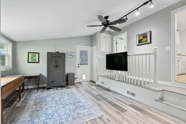 living room with rail lighting, light hardwood / wood-style flooring, ceiling fan, and lofted ceiling