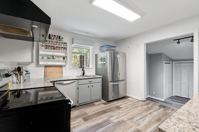 kitchen with stainless steel appliances, light stone counters, light hardwood / wood-style floors, and sink