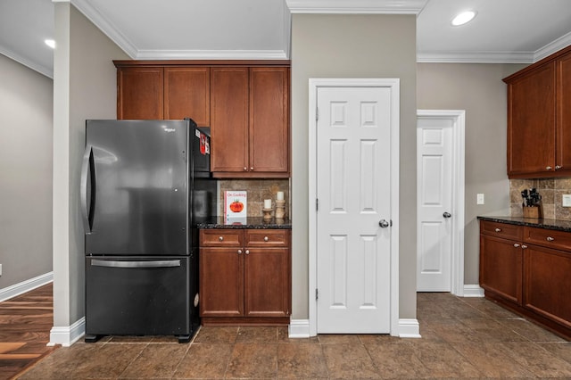 kitchen with backsplash, stainless steel refrigerator, and dark stone counters