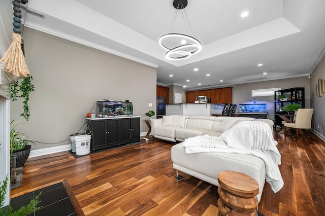 living room featuring dark hardwood / wood-style flooring, a tray ceiling, an inviting chandelier, and crown molding