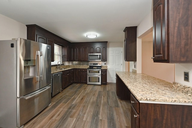 kitchen featuring sink, tasteful backsplash, dark hardwood / wood-style flooring, dark brown cabinetry, and stainless steel appliances