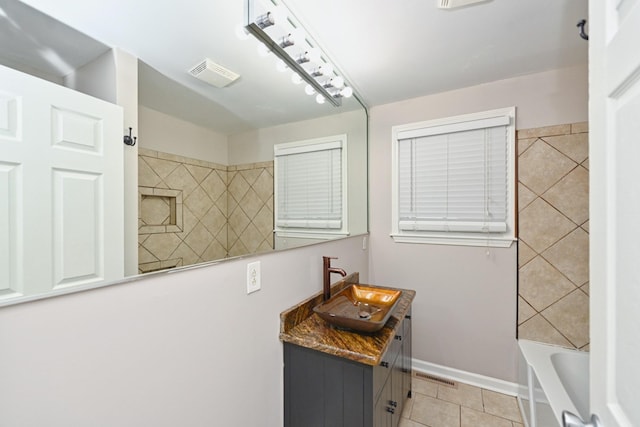 bathroom with tile patterned flooring, vanity, and tiled shower / bath