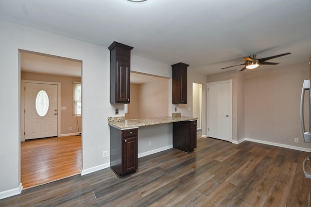 kitchen with light stone countertops, ceiling fan, dark brown cabinets, and dark wood-type flooring