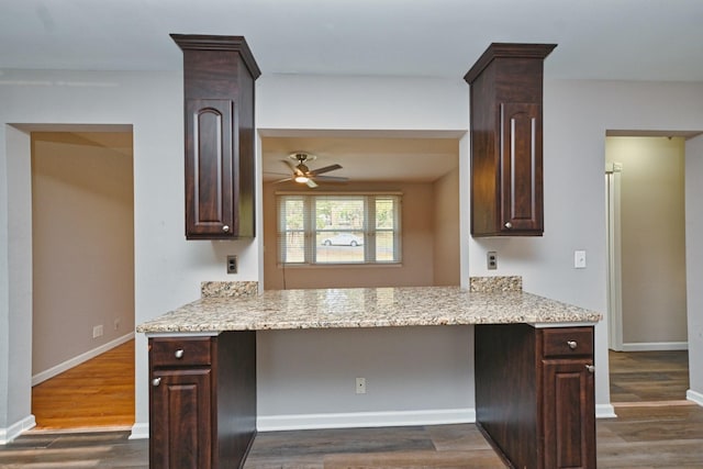 kitchen featuring built in desk, dark brown cabinetry, and dark wood-type flooring