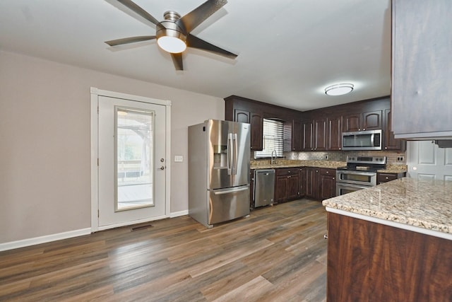 kitchen with dark brown cabinetry, light stone counters, a wealth of natural light, and appliances with stainless steel finishes