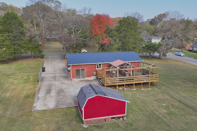 rear view of house with a storage shed, a yard, and a deck