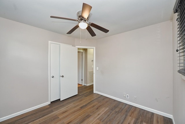 unfurnished bedroom with ceiling fan and dark wood-type flooring