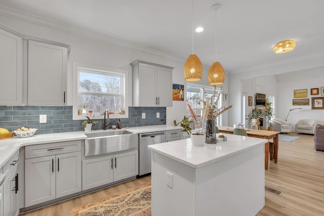 kitchen with pendant lighting, backsplash, sink, light hardwood / wood-style flooring, and stainless steel dishwasher