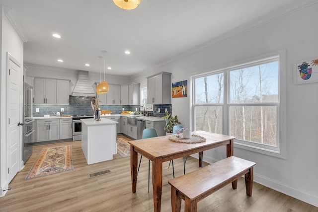 kitchen with premium range hood, gray cabinets, decorative light fixtures, a kitchen island, and stainless steel appliances