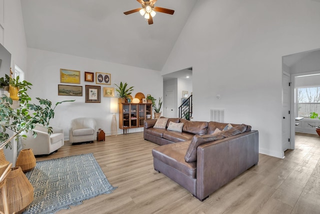 living room with ceiling fan, light hardwood / wood-style flooring, and high vaulted ceiling