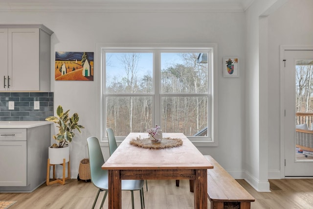 dining space featuring light hardwood / wood-style floors, ornamental molding, and a wealth of natural light