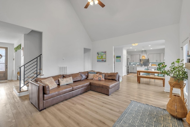 living room featuring ceiling fan, light wood-type flooring, sink, and high vaulted ceiling