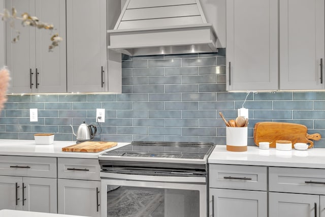 kitchen featuring decorative backsplash, premium range hood, and electric stove