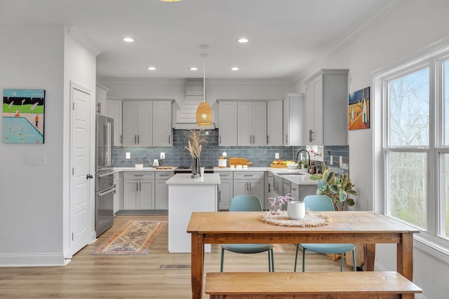 kitchen featuring pendant lighting, custom exhaust hood, gray cabinetry, ornamental molding, and a kitchen island