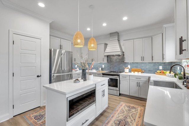 kitchen with custom exhaust hood, a center island, hanging light fixtures, sink, and appliances with stainless steel finishes