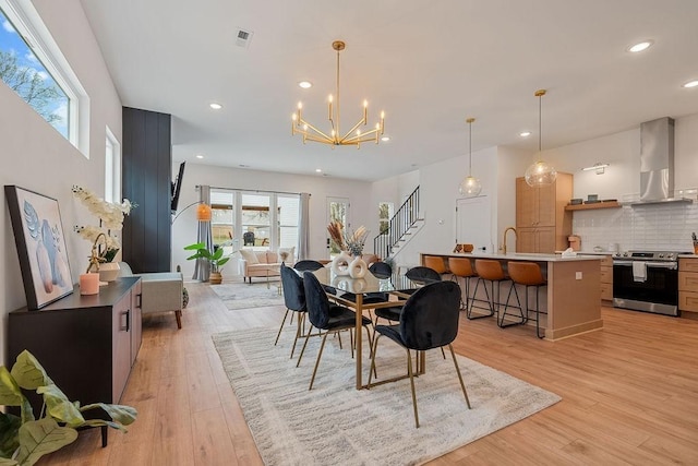 dining space with light wood-type flooring, sink, and a chandelier