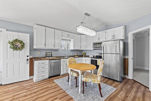 kitchen featuring a textured ceiling, white cabinetry, stainless steel appliances, and decorative light fixtures